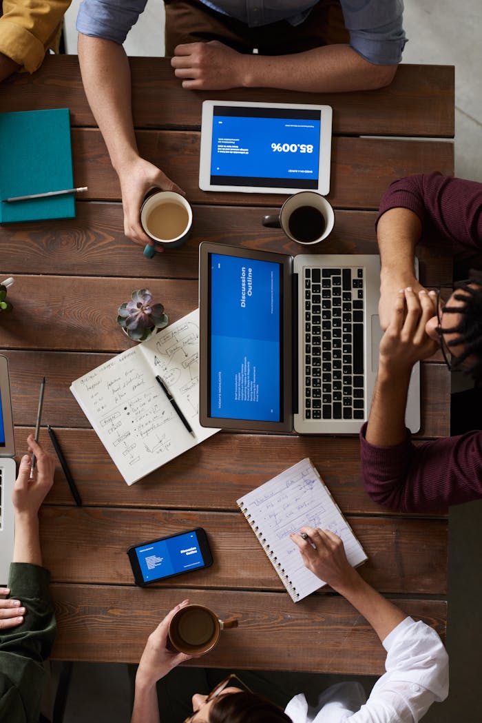 Home Group of coworkers discussing business strategies with laptops and tablets in a modern office setting.