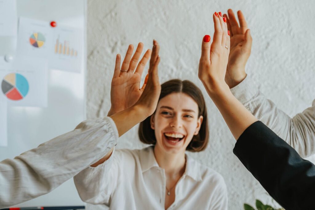pexels photo 8145344 Diverse colleagues share a joyful high five, showcasing teamwork and unity in the office.